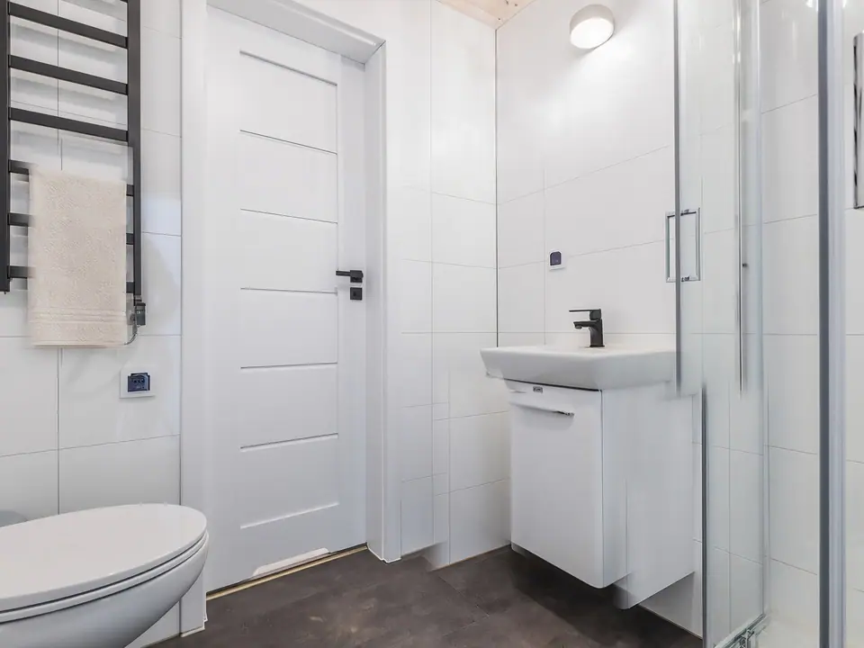 Bad mit Dusche, Waschtisch mit Unterschrank, WC und schwarzem Handtuchheizkörper. Visualisierung